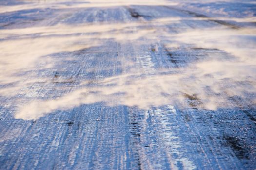 Close up of ice covered road with tire marks.