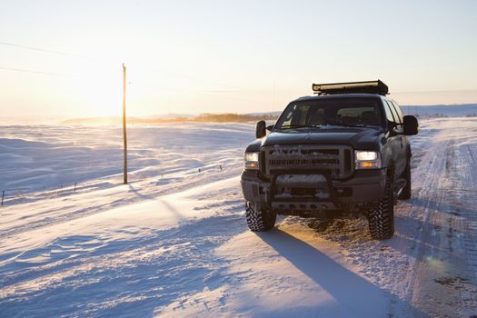 Truck on ice covered road and snowy rural landscape.