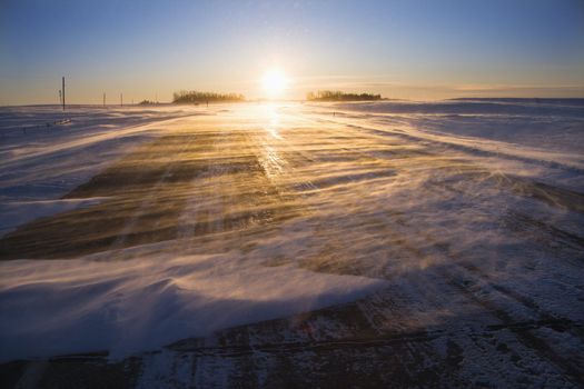 Ice covered road with sun rising in distance.