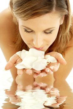 lovely woman in water smelling white rose petals
