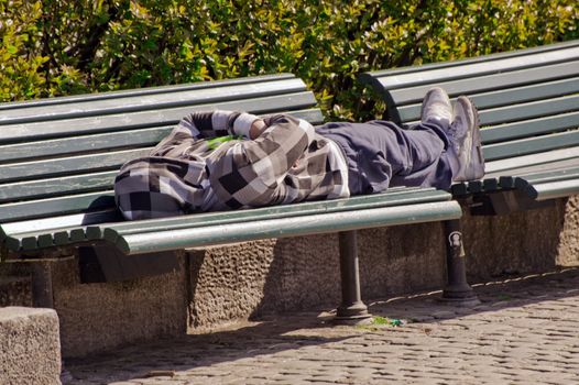  The man sleeps on a bench in city park