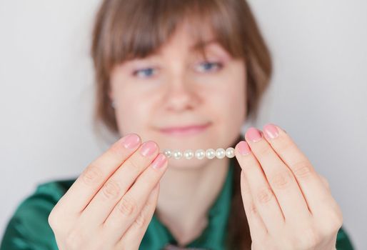 The young girl admires a beads from pearls close up