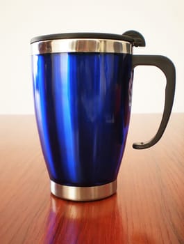 Stainless steel travel mug on a wooden table