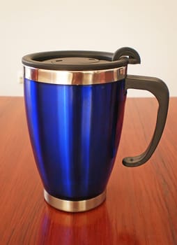 Stainless steel travel mug on a wooden table