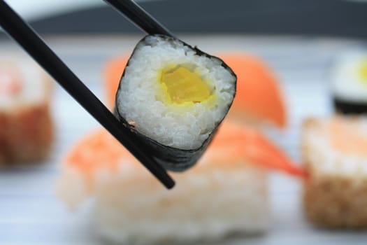 A piece of traditional Japanese sushi between chopsticks