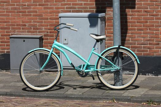 A new light blue bikes parked on a street