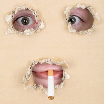 Eyes and lips look out from hole in cardboard 