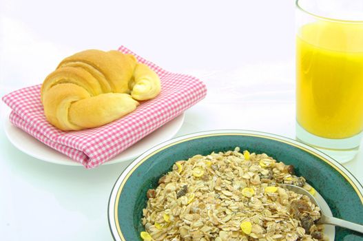 A fresh, healthy breakfast of muesli, a croissant, and orange juice