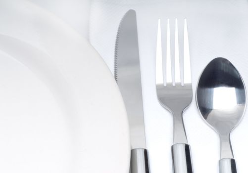 close up of a cutlery set on a table with napkin and dish