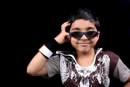 A smart Indian boy posing with style, on black studio background.