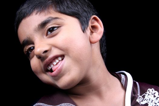 A portrait of a cute Indian boy, on black studio background.