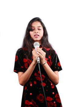 A beautiful Indian teenage girl singing a prayer, on white studio background.