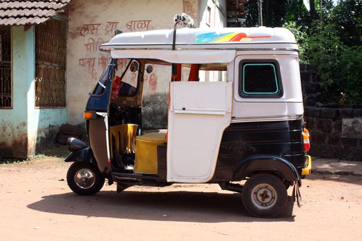 An Indian auto-rickshaw parked on an Indian village road.