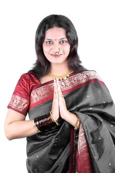 A beautiful smiling Indian woman in a traditional gray saree with a welcome gesture of Namaste, used in India like Hello in western countries.