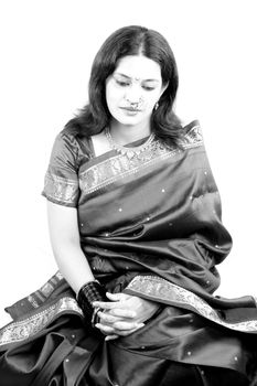 A classic image of a depressed Indian woman in a traditional attire, on white studio background. High contrast Image.