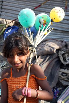 A cute little beggar girl from India with colorful balloons, in a happy mood.