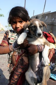 A little beggar girl from India wearing torn sari(Indian clothing), proudly holding her pet dog.