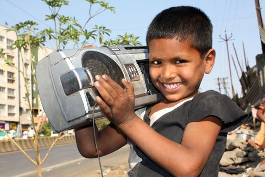 A streetside Indian kid carrying is favorite possession - The music Boombox.