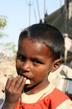 A portrait of a poor & sick Indian boy eating food.