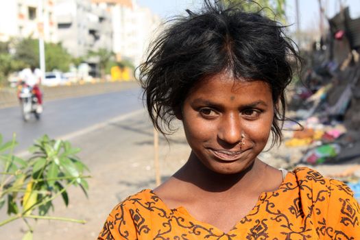 A portrait of a anxious looking teenage beggar girl in the streetside, in India.