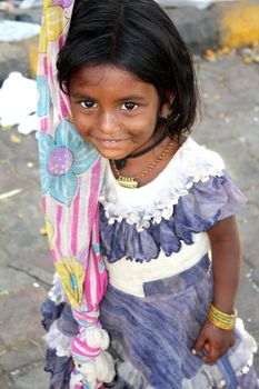 A shy Indian beggar girl looking at the camera.