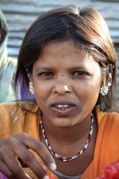 A portrait of a poor Indian teenage girl in traditional orange dress.