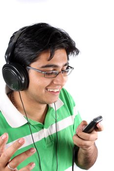 An Indian teenager listening to music on his headphones and a MP3 cellphone, on white studio background.
