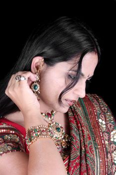 A beautiful woman checking her traditional ear-ring that she wearing along with her traditional attire, for a festival.