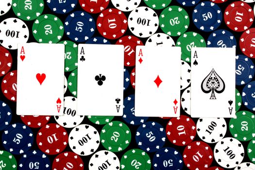 A poker hand of 'Four of a Kind' consisting of 4 aces in this case, on colorful gambling chips.