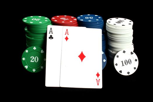 A winning hand of poker made of a pair of Aces with poker chips, on black studio background.