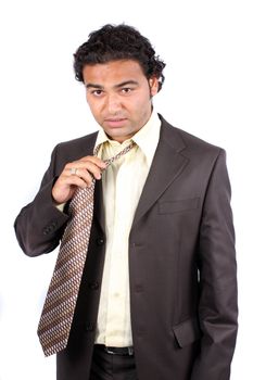 A tied Indian businessman removing his tie, on white studio background.