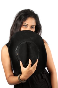 A metaphorical portrait of a mysterious Indian woman hiding behind a hat, on white studio background.