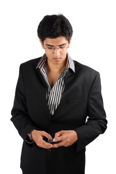 A young Indian businessman in a suit sending a text message using his cellphone, on white studio background.