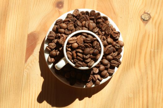 Cup full of coffee beans on wooden background