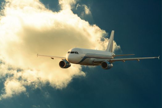 Passenger airplane on background with dark sunset sky and clouds