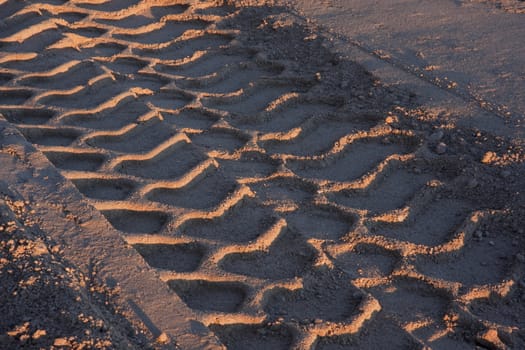 big tire tracks in sand at construction site, sunset light