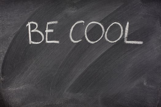Be Cool phrase handwritten with white chalk on a blackboard with eraser smudges