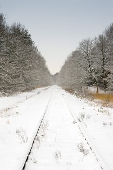 snow landscape and railway track with pale blue sky
