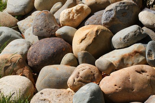 Pile of multi colored river rocks with some grass