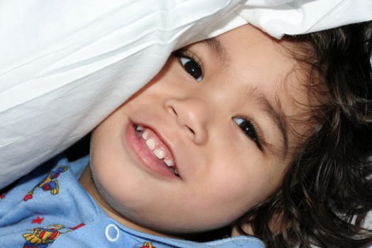 Little boy in hospital gown peeking under pillow