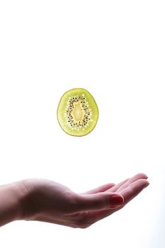 soar of slice kiwi  in air over palm on white background