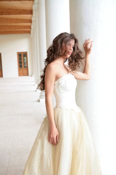 romantic portrait of the beautiful girl in white-golden gown near pillars