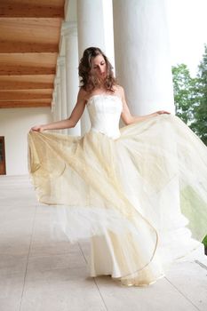 bride in white-golden gown dances amongst pillars