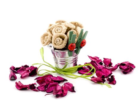 Handmade flowers in small bucket and pink potpourri on white background