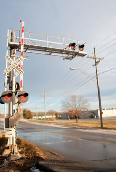 Railroad crossing sign on road under blue sky