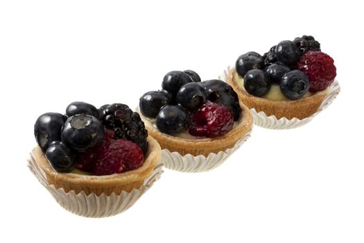 three mini fruit tarts with bklueberries, raspberries and blackberries, isolated on white
