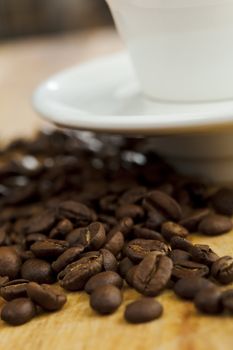 Coffee beans on the table with white coffee cup. Shallow dof.