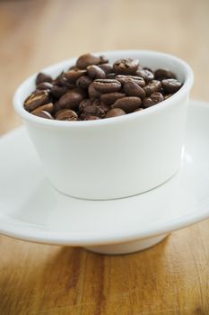 Small white cup filled with brown coffee beans