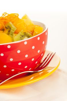 Fruit salad on the white dotted bowl (kiwi, orange, pinapple, banana etc).