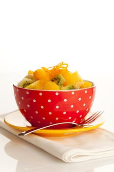 Fruit salad on the white dotted bowl (kiwi, orange, pinapple, banana etc).